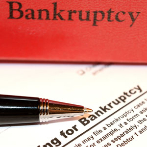 Close-up of a pen on a bankruptcy document with a red book titled Bankruptcy in the background